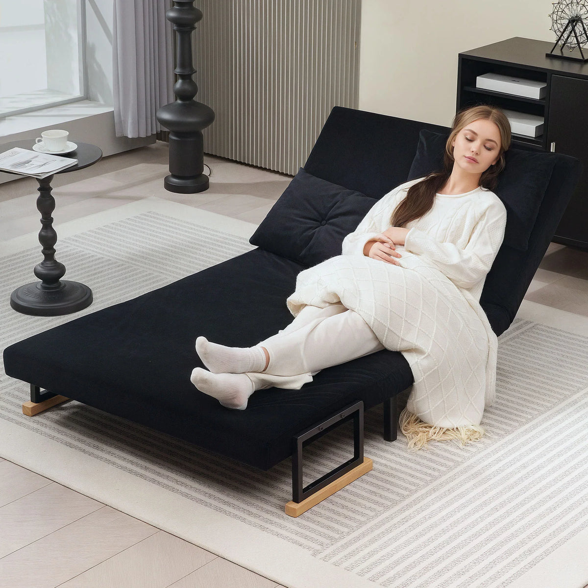 Black sofa bed with tufted back, wooden armrests, and extended chaise surface