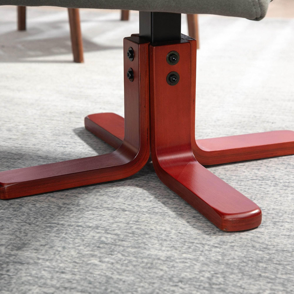 Close-up of grey recliner’s red wooden base and support legs on carpet.