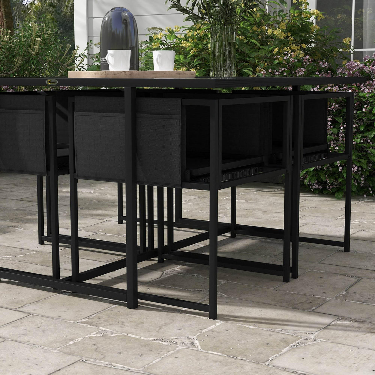 Black outdoor dining table with four matching mesh chairs, side view