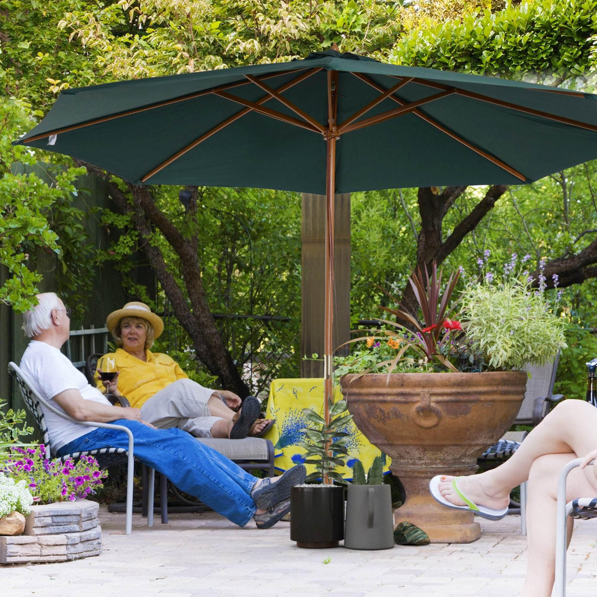 Dark green patio garden parasol with wooden pole and extended canopy over outdoor seating