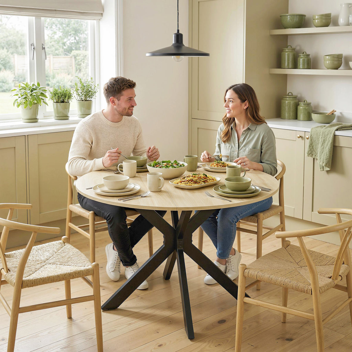 Round drop-leaf dining table with black base in a bright kitchen-dining space