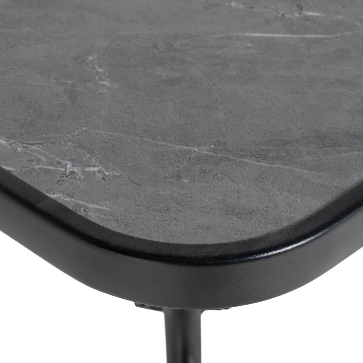 Close-up corner of dark gray tabletop with smooth rounded edge and black metal leg