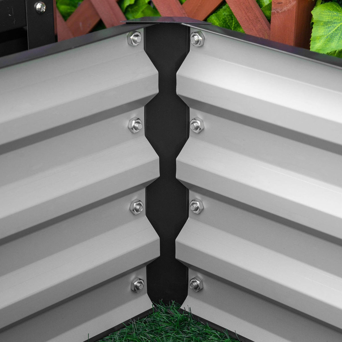 Corner joint of dark grey raised garden bed with bolts and slatted panels