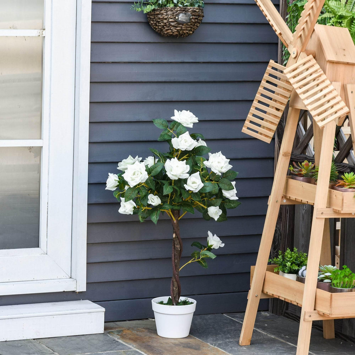 Artificial white rose tree with white blossoms and green leaves in a white pot