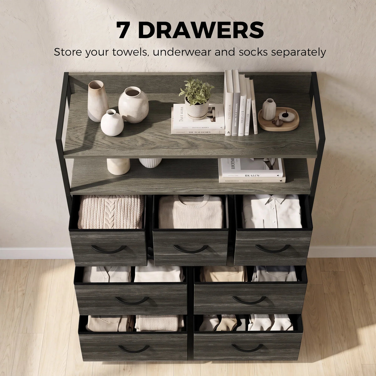 Grey wood-effect dresser with open top shelves holding folded linens and three drawer rows