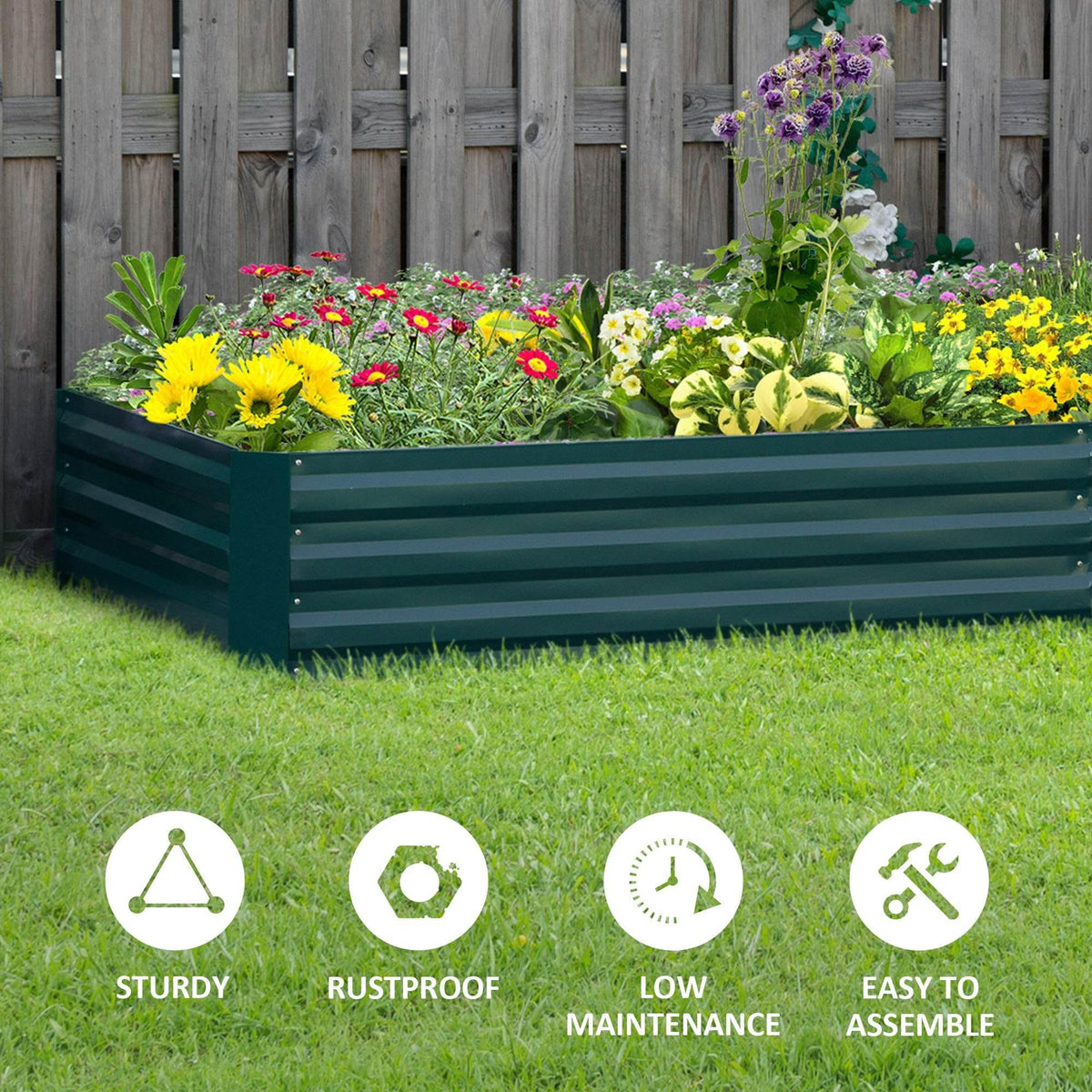 Green raised garden bed planter box with colorful flowers and greenery on a lawn