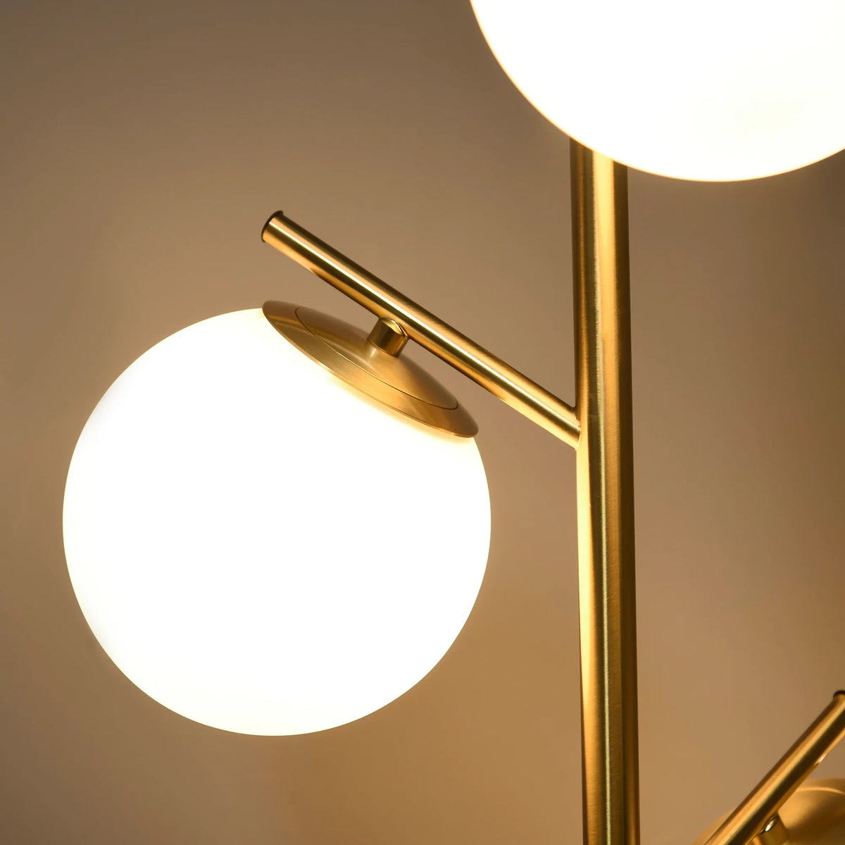Gold-tone floor lamp close-up with two globe glass shades and angled arms