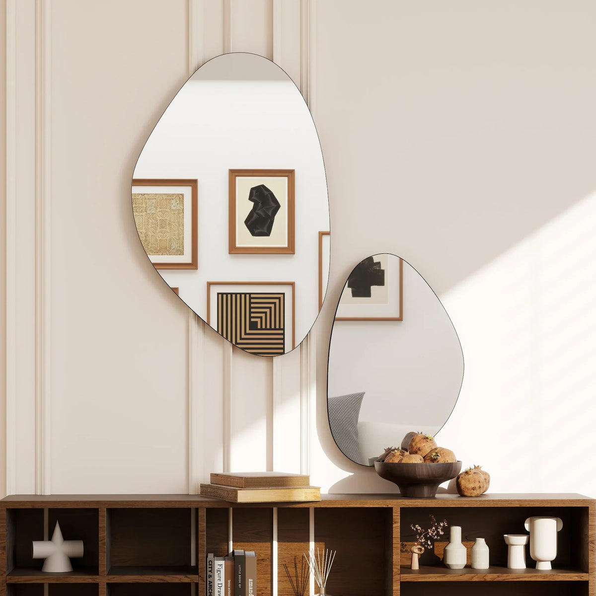 Set of 2 pebble-shaped wall mirrors with black metal frames, reflecting wall artwork