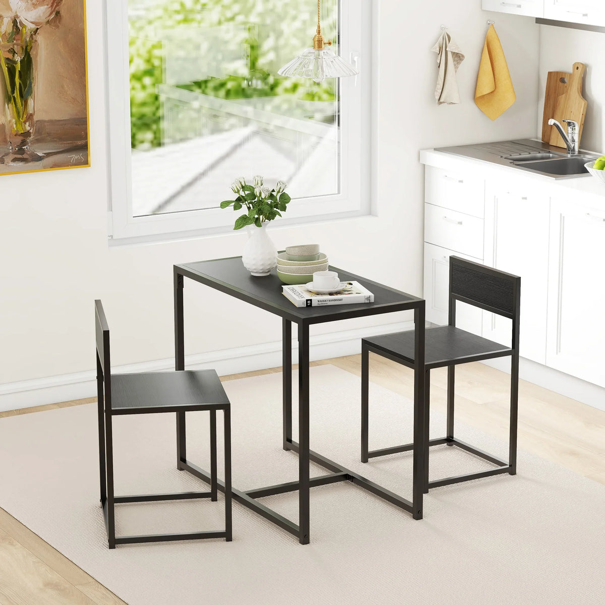 Black rectangular dining table with two chairs in a bright kitchen