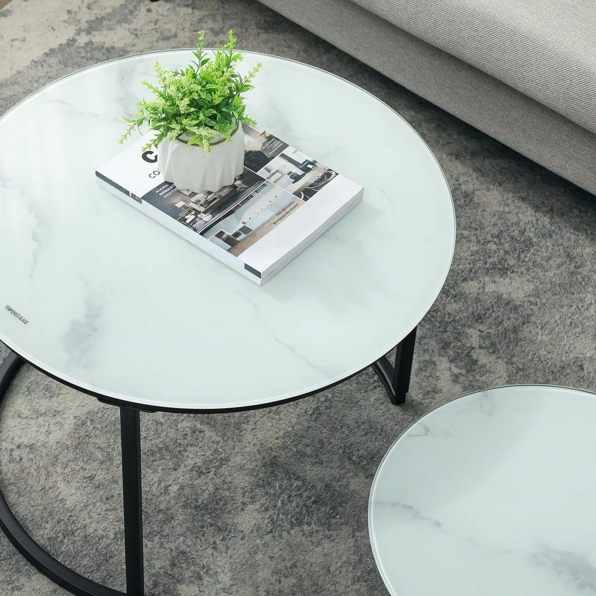 Round nesting coffee table pair with marble-effect glass tops and black steel oval ring base