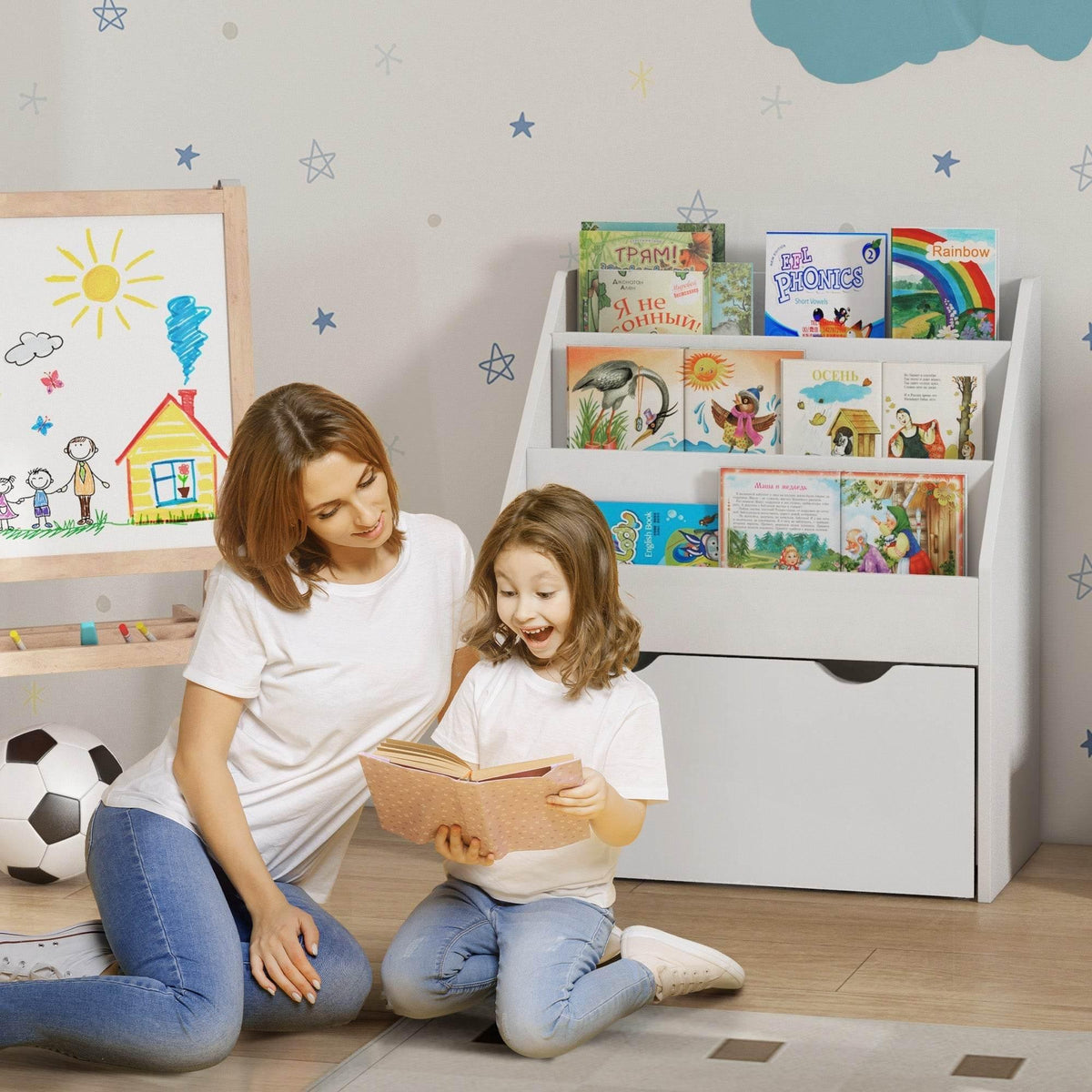 White children’s bookcase with open shelves and front drawer; kids reading beside it