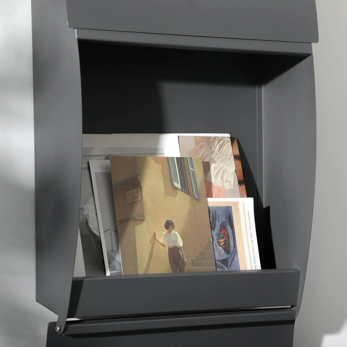 Open anthracite wall mailbox with delivered mail inside and frosted viewing window