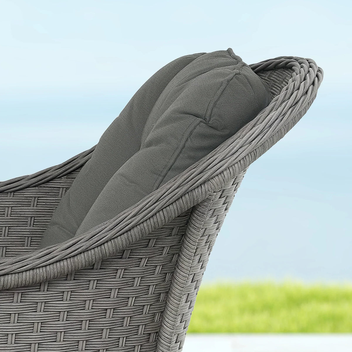 Dark gray woven rattan-style armrest and cushion edge close-up on an outdoor chair