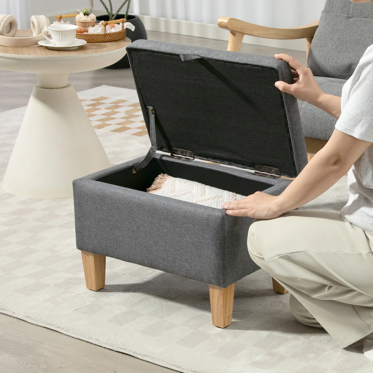 Charcoal grey storage ottoman with hinged lid open, showing the padded compartment