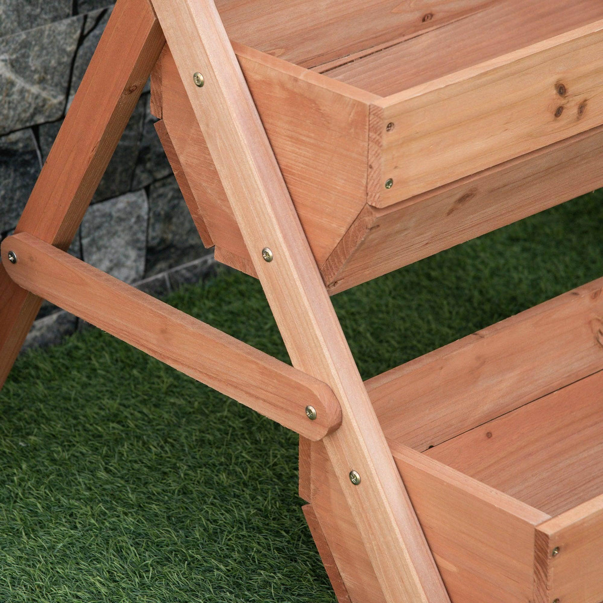 Close-up of brown raised planter box frame with wooden slats, metal screws, and angled leg
