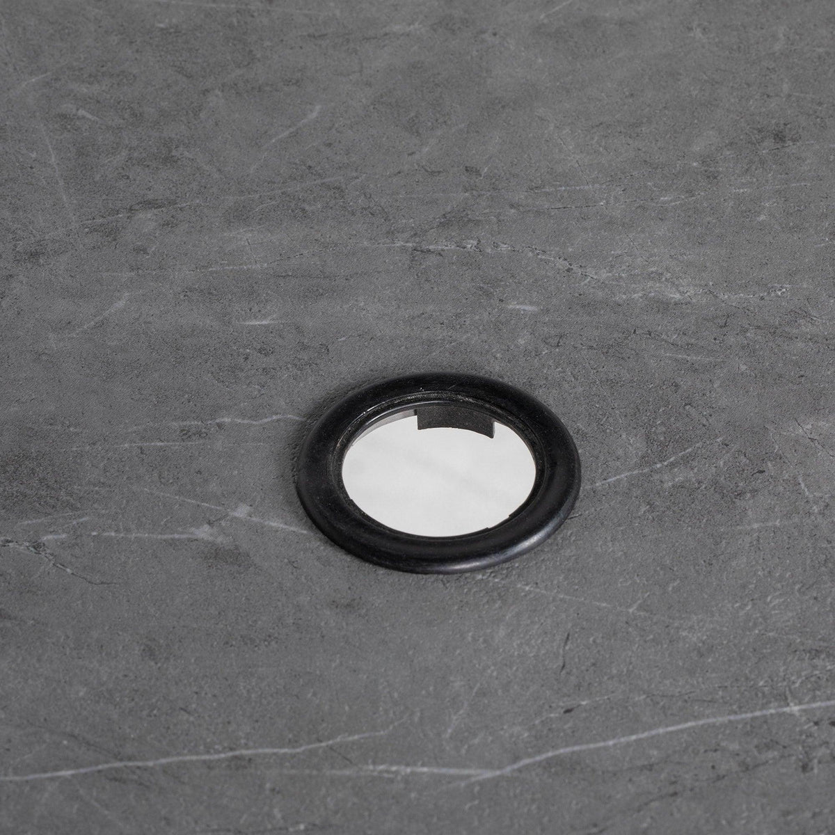 Round umbrella hole opening on dark gray faux-marble tabletop with black ring