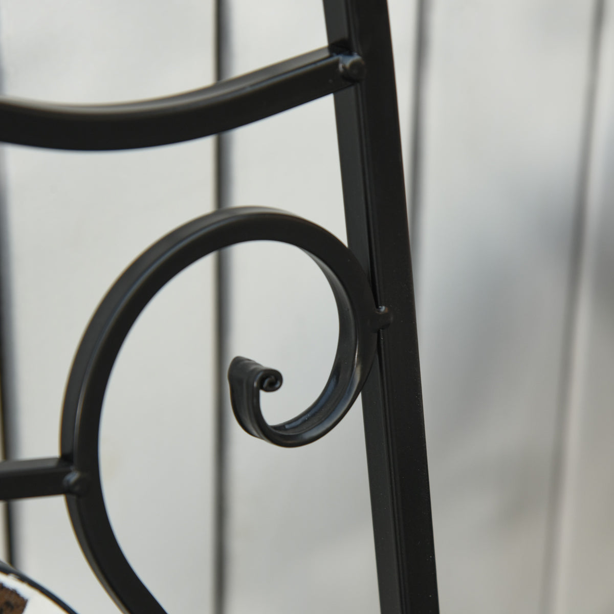 Close-up of black metal chair frame with curved scroll handle detail