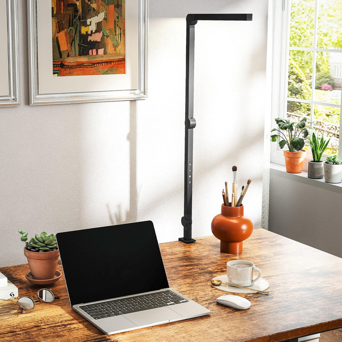 Black LED desk lamp with clamp base standing on work desk near laptop