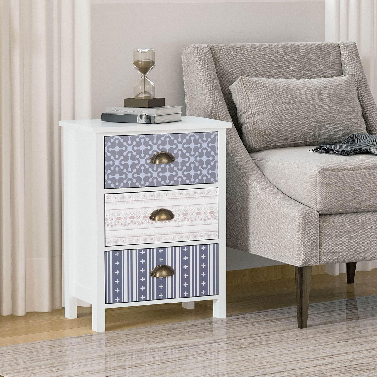 White nightstand with 3 patterned drawers and antique brass cup pulls, beside gray sofa