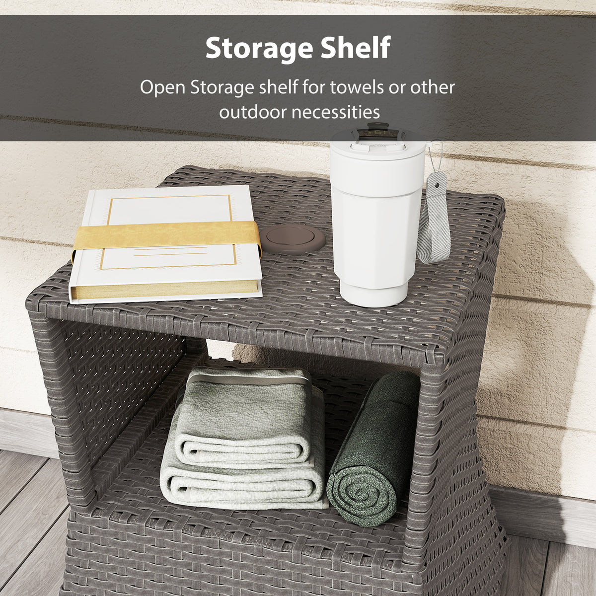 Dark grey wicker outdoor side table with open shelf holding folded towels