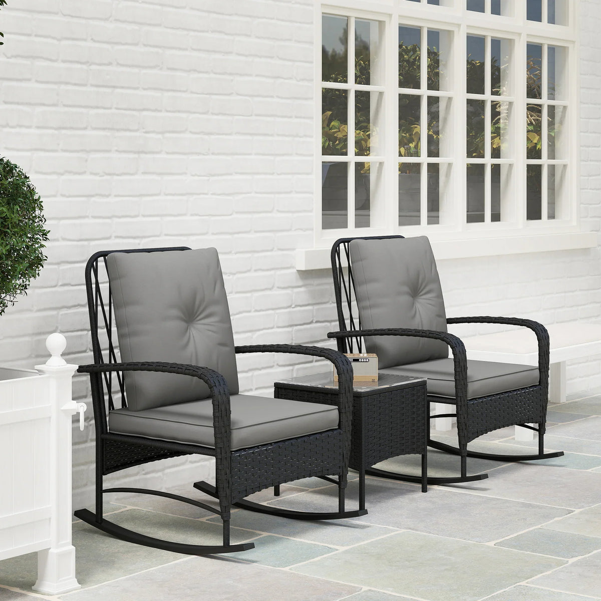 Two black rattan rocking chairs with gray cushions and a small bistro table