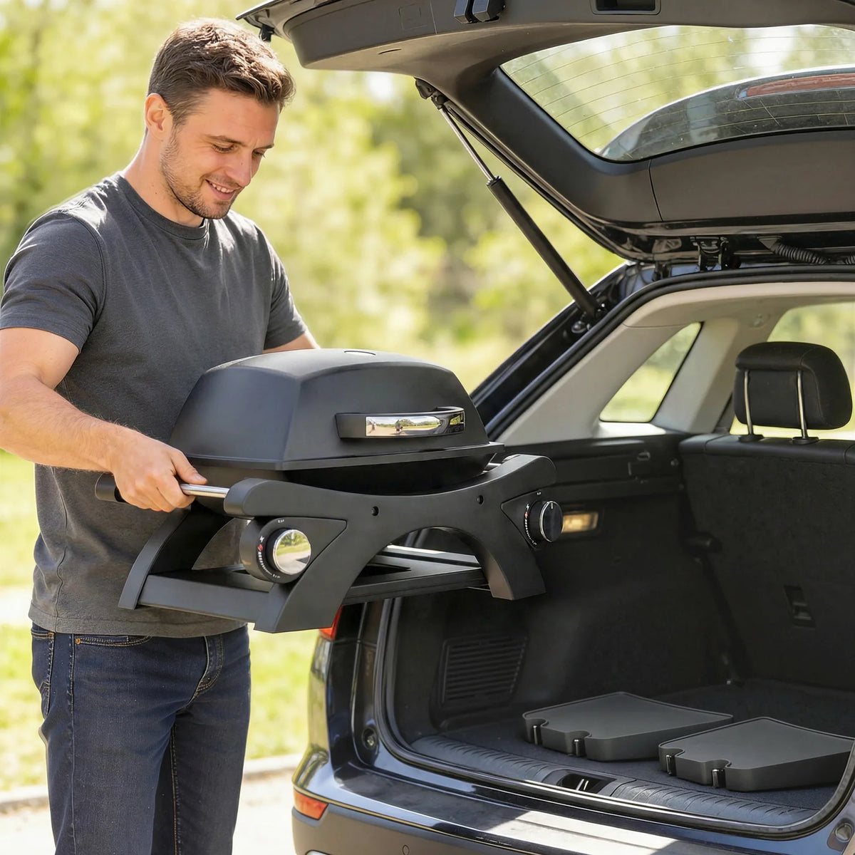 Man using black gas grill from open hood, showing burners and cooking surface