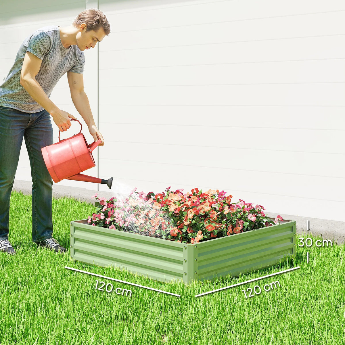 Light green raised planter box filled with flowers as a watering can pours
