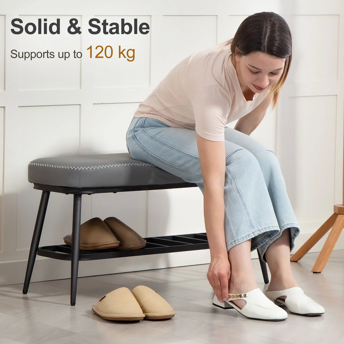 Grey shoe storage bench with cushioned seat and open shelf, shown placing slippers