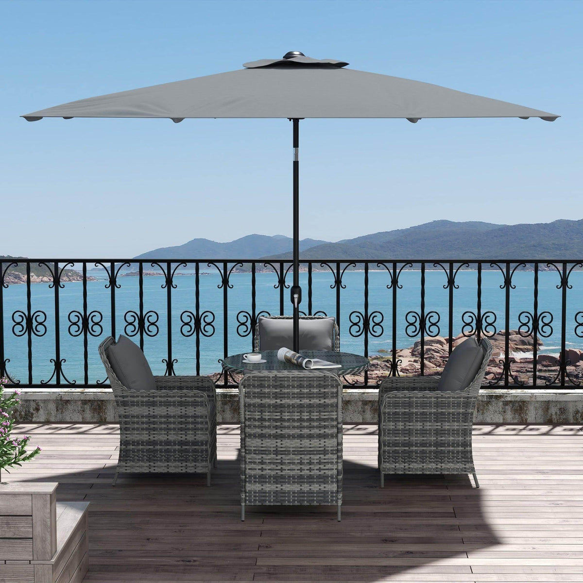Outdoor dining set with gray rattan chairs and round glass-top table under umbrella