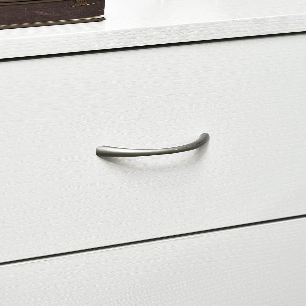 Close-up of white nightstand drawer with curved metal handle