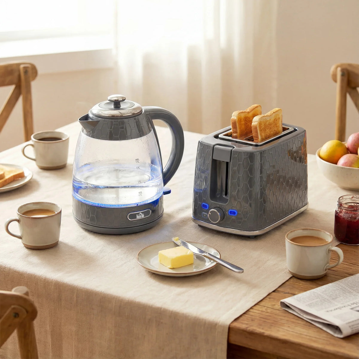 Grey electric kettle and 2-slice toaster set on a table with cups and toast.