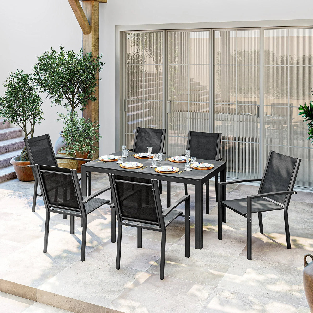 Black patio dining table with four stackable mesh chairs around