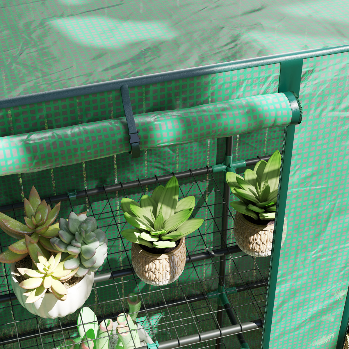 Green three-tier mini greenhouse with wire shelves holding potted plants