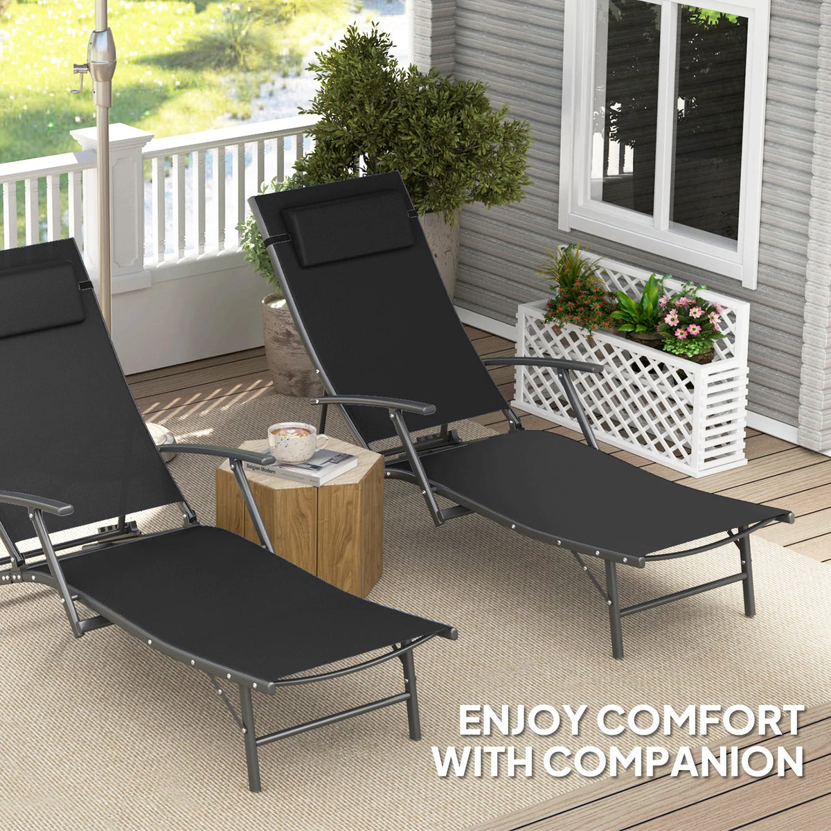 Two black adjustable sun loungers with cushioned pillows on outdoor porch flooring