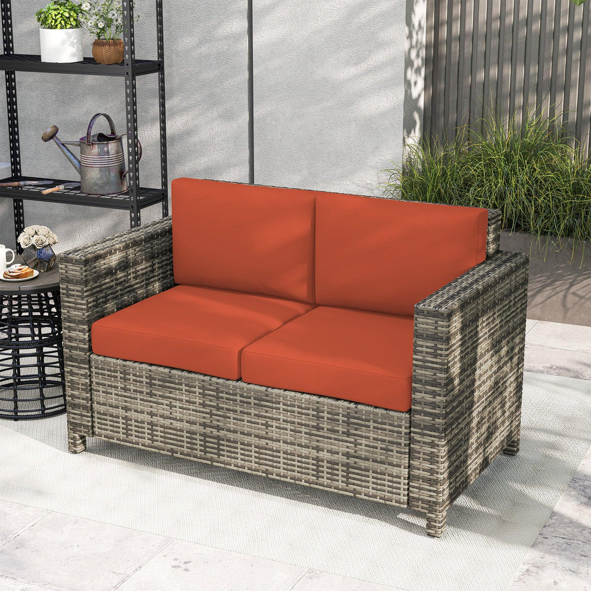 Grey woven rattan 2-seater loveseat with orange seat cushions and armrests