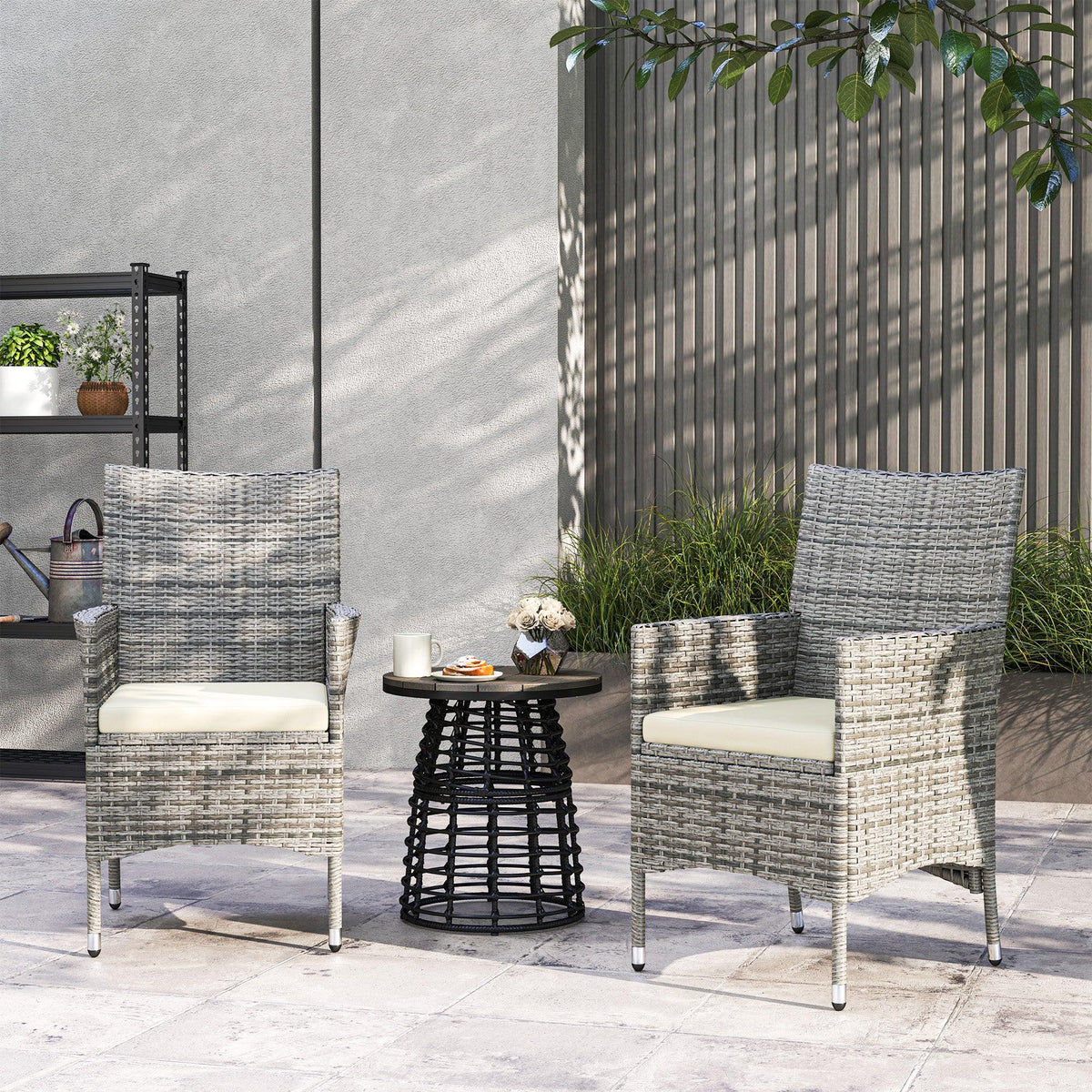 Two grey rattan dining chairs with cream seat cushions and metal legs on patio