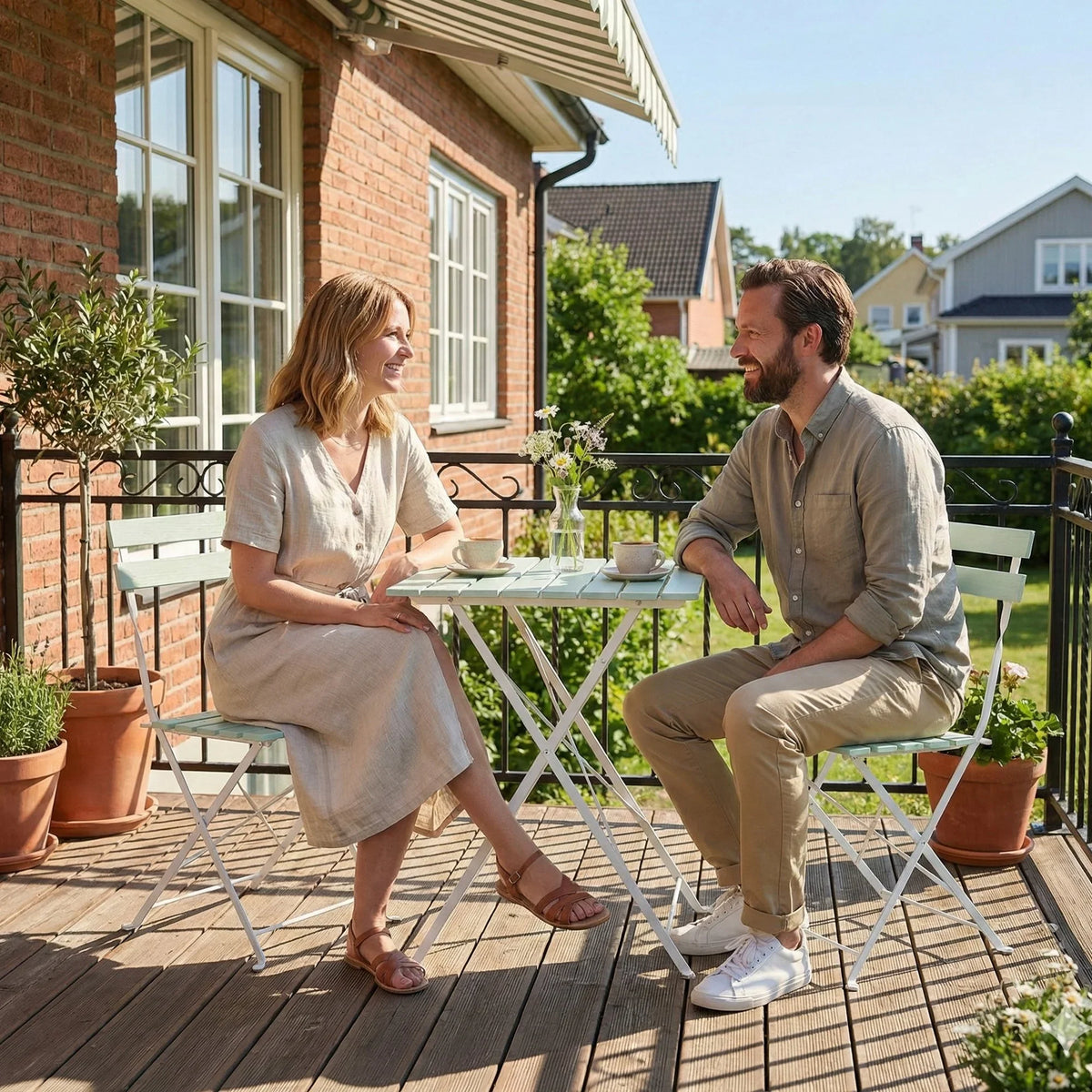 Outdoor folding bistro set on deck: green slat tabletop and two white metal chairs