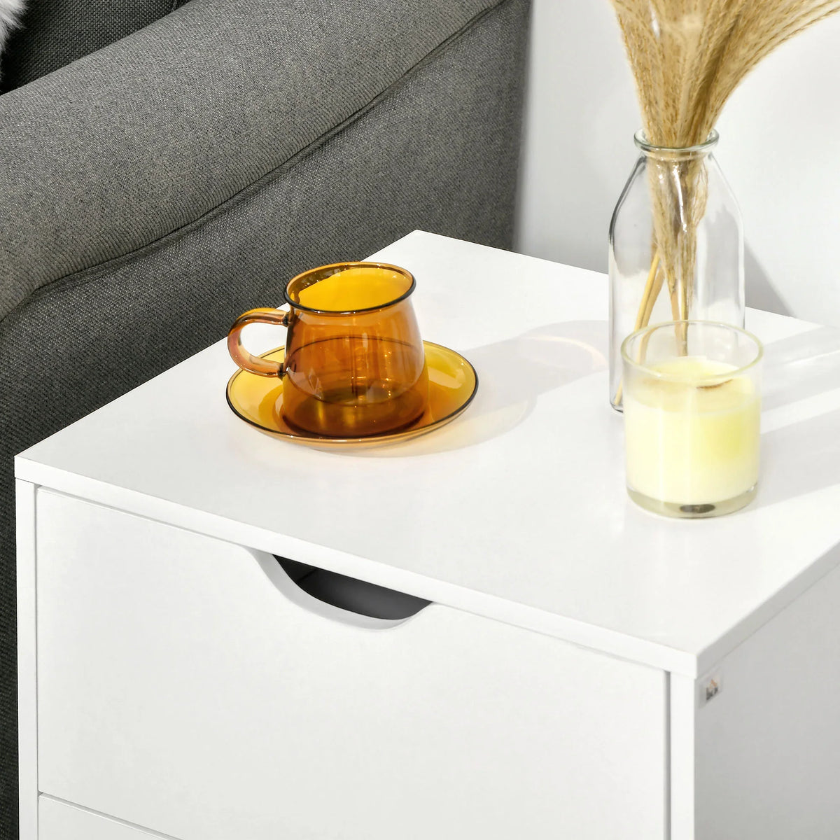 White bedside table with black curved drawer pull, smooth tabletop and pine legs.