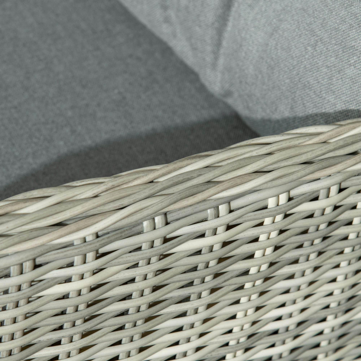 Close-up of light grey woven rattan wicker with dark grey cushion fabric