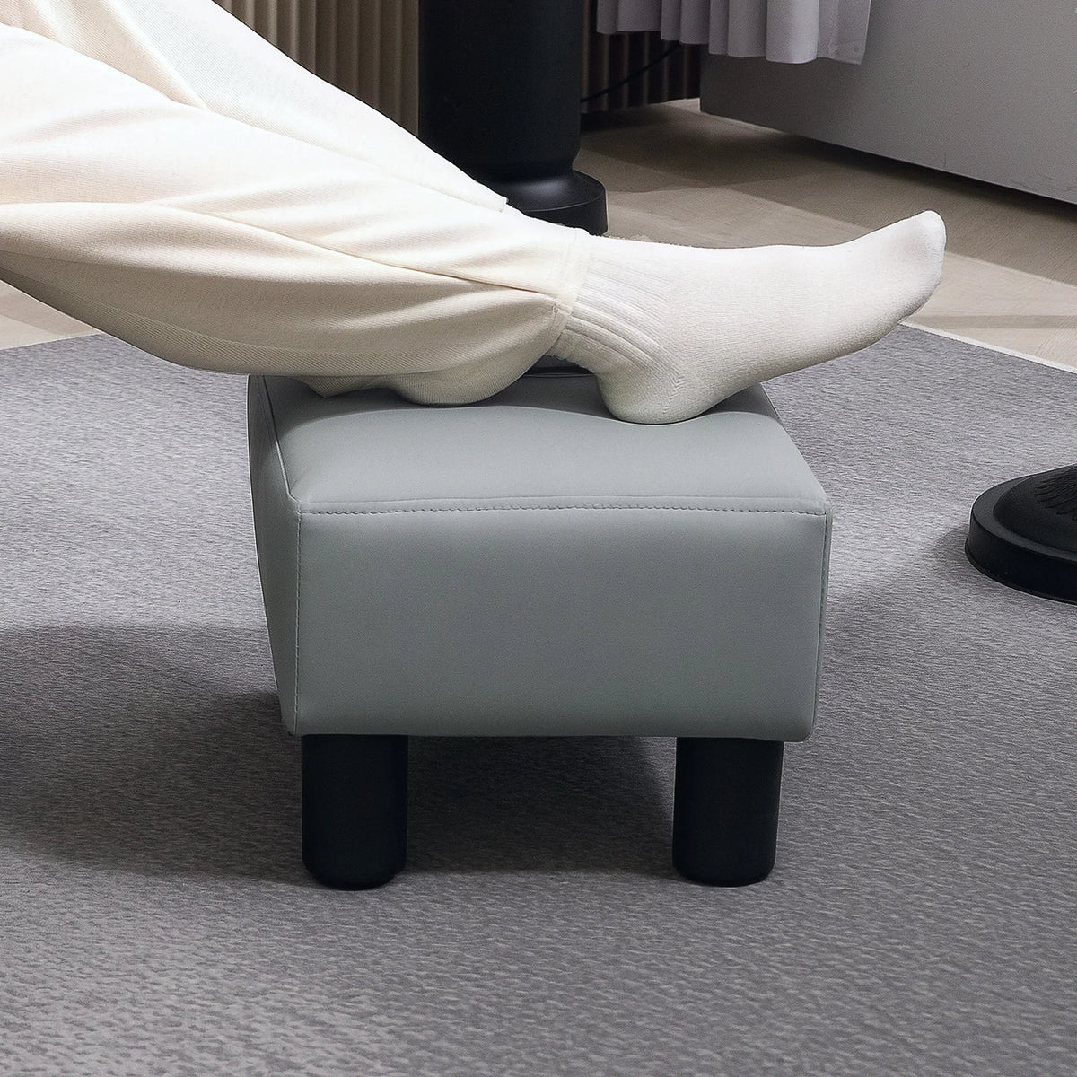 Gray PU leather footstool with square padded cushion and four black legs