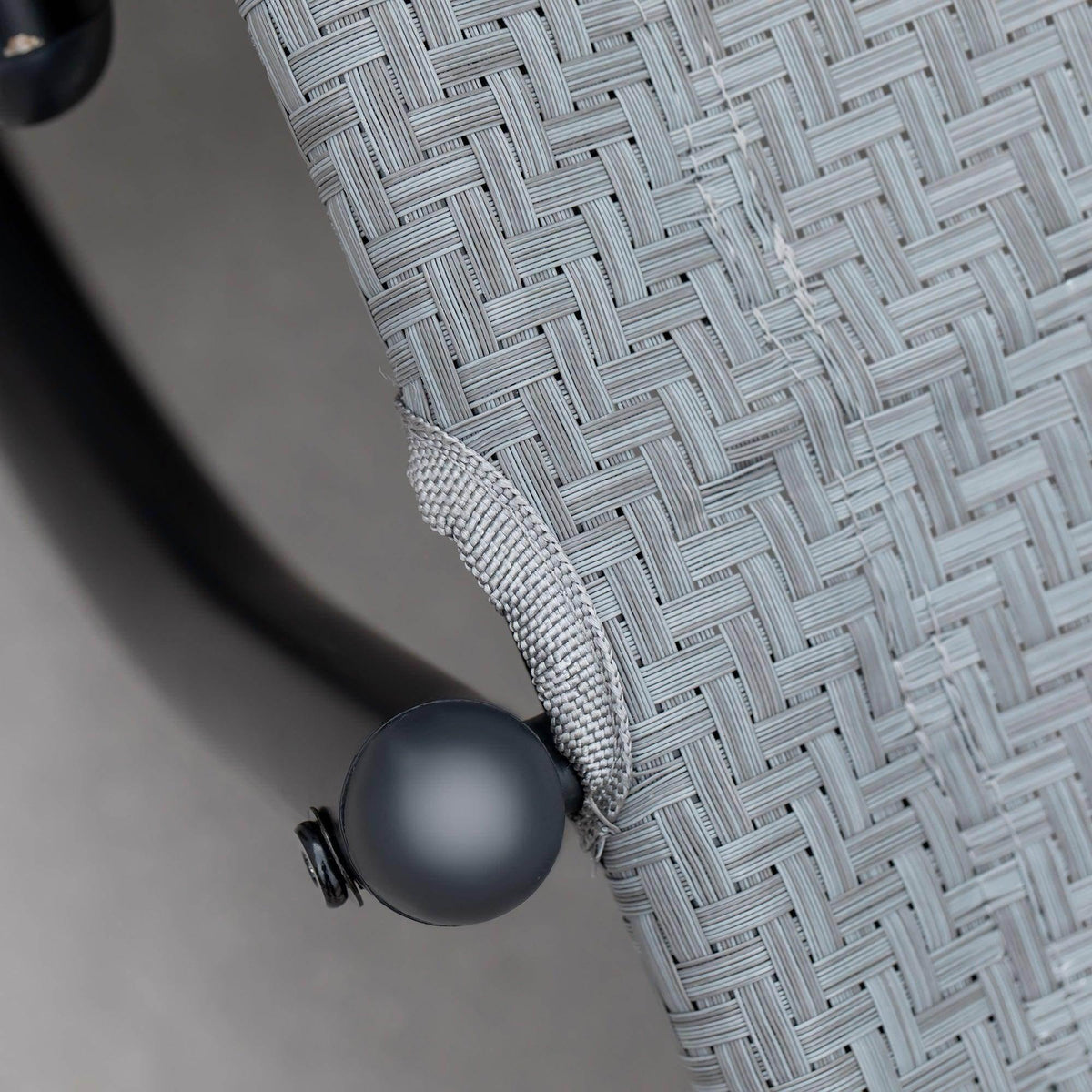 Grey rattan-effect seat fabric corner with black round connector detail