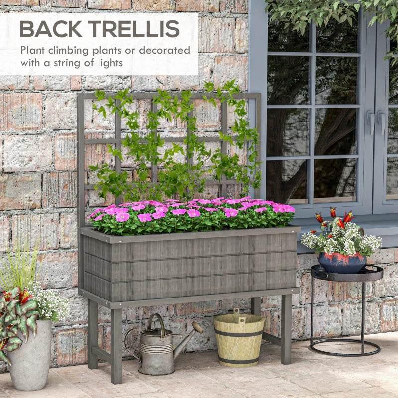 Grey wooden raised planter with back trellis, pink flowers in the rectangular bed