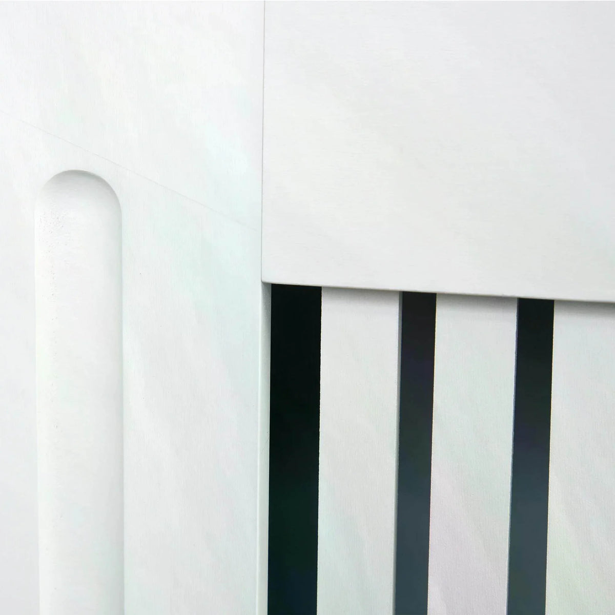White radiator cover close-up of vertical slatted vent and curved cabinet side
