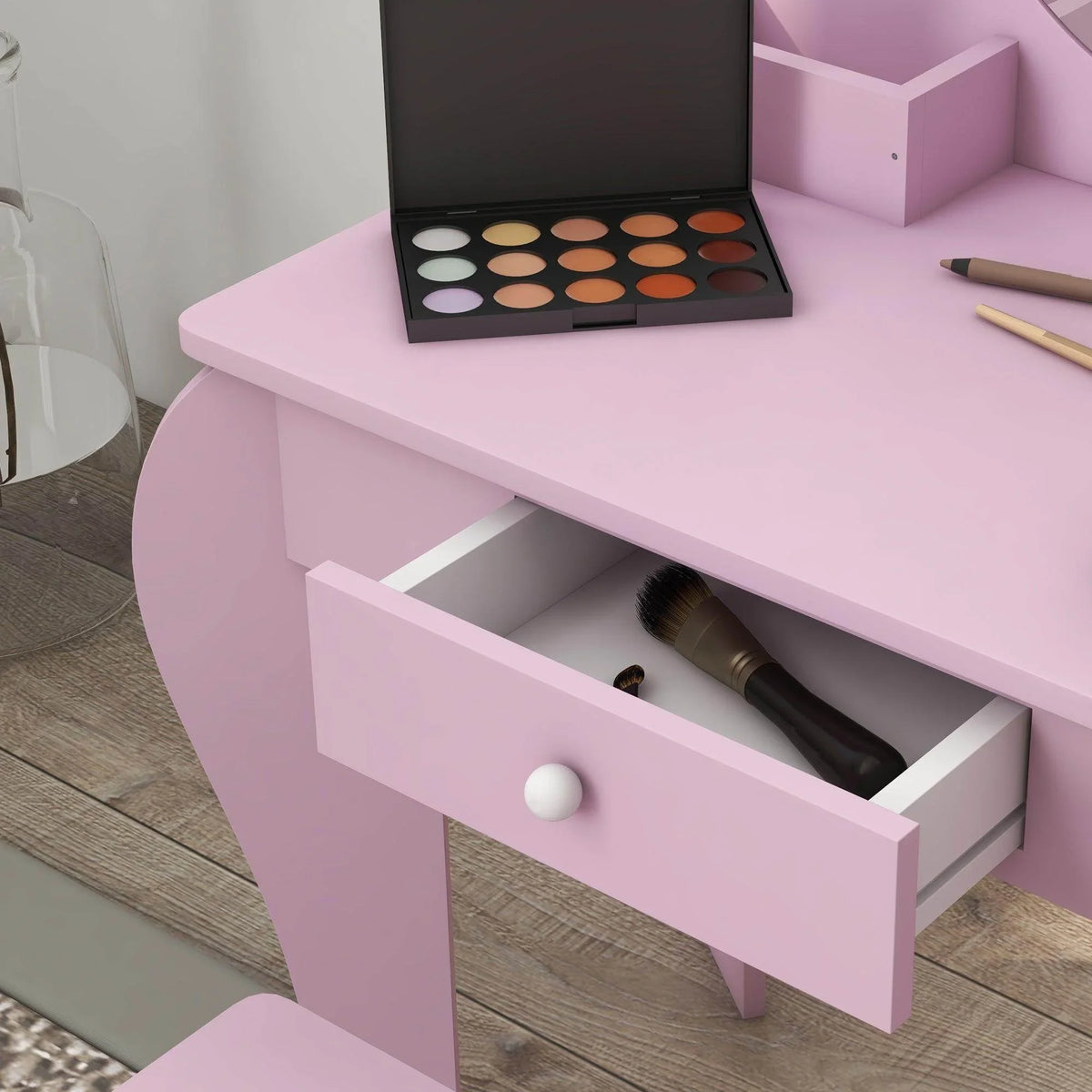 Pink vanity table with open drawer and makeup palette on tabletop
