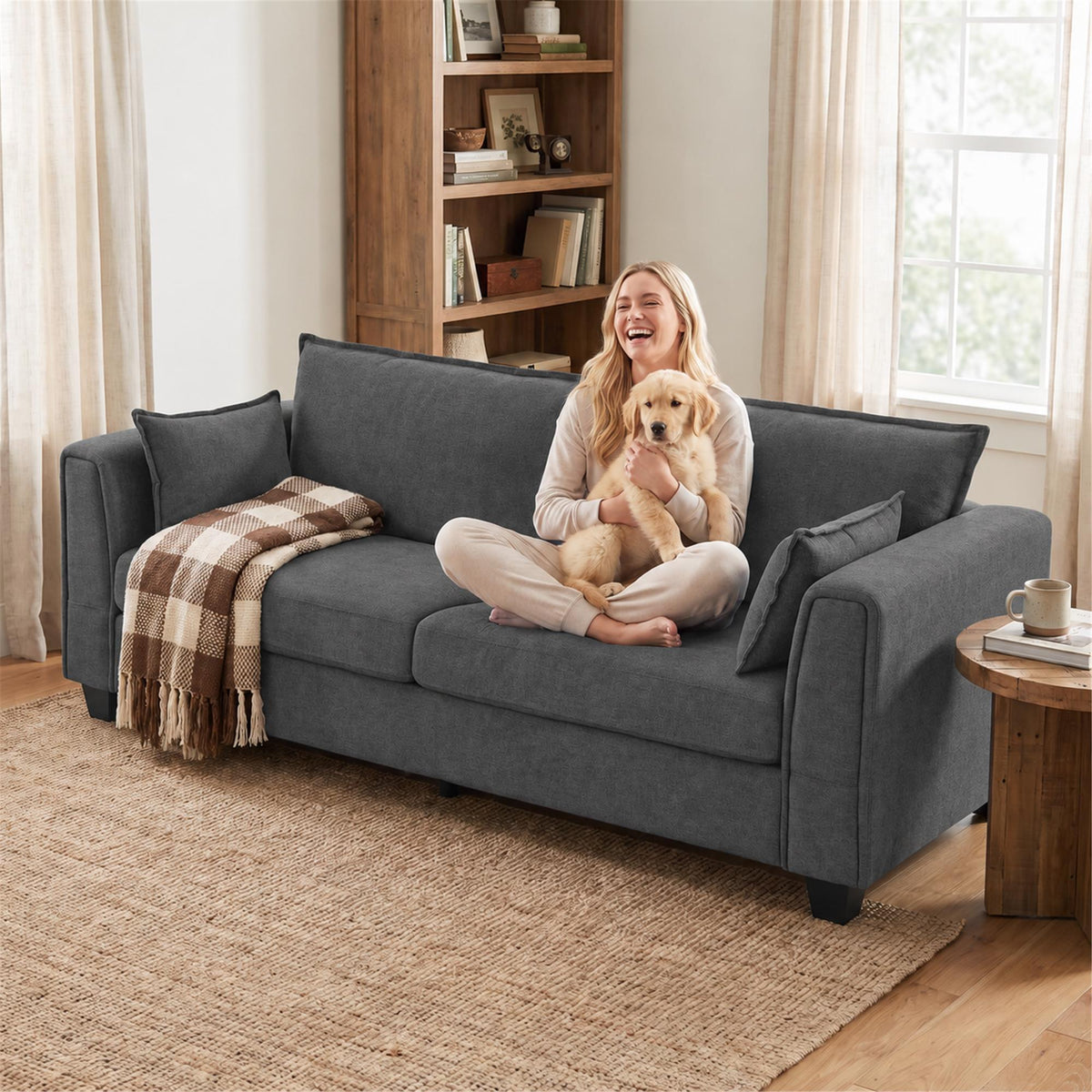 Dark grey 3-seater sofa with two accent pillows and padded arms, pet resting on seat.