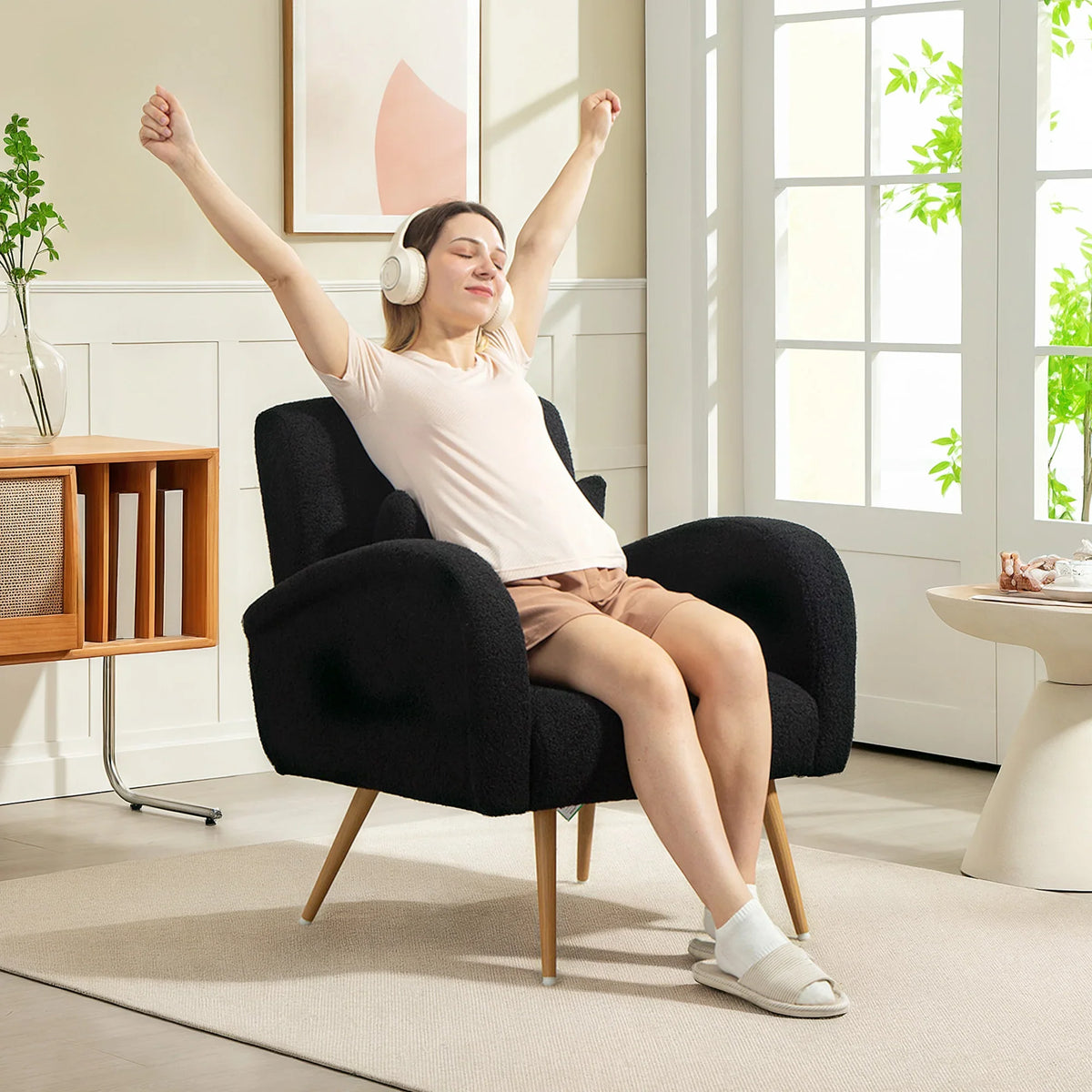 Black teddy fleece accent chair with curved arms and wooden legs, seated view