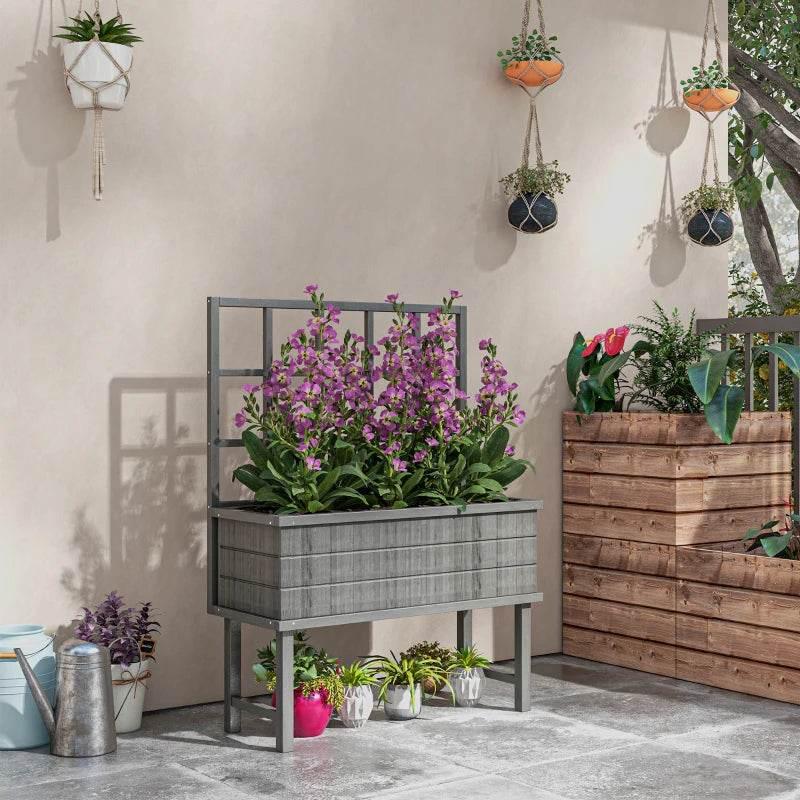 Grey wooden raised garden planter with back trellis and purple flowering plants