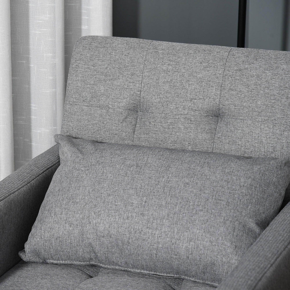 Grey upholstered sofa bed with tufted back cushions and thick seat pad