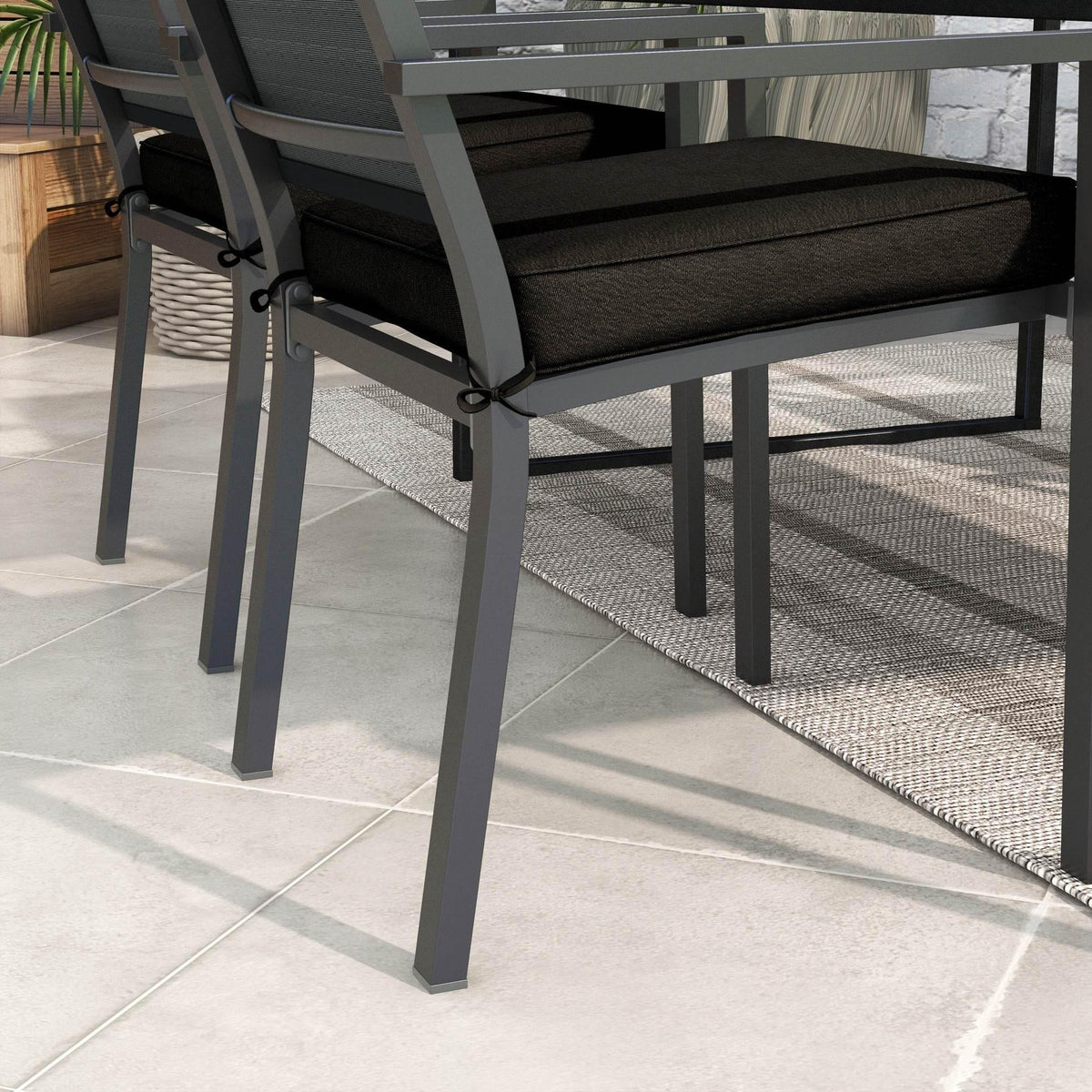 Black square patio chair cushion secured with ties on a bench-style chair