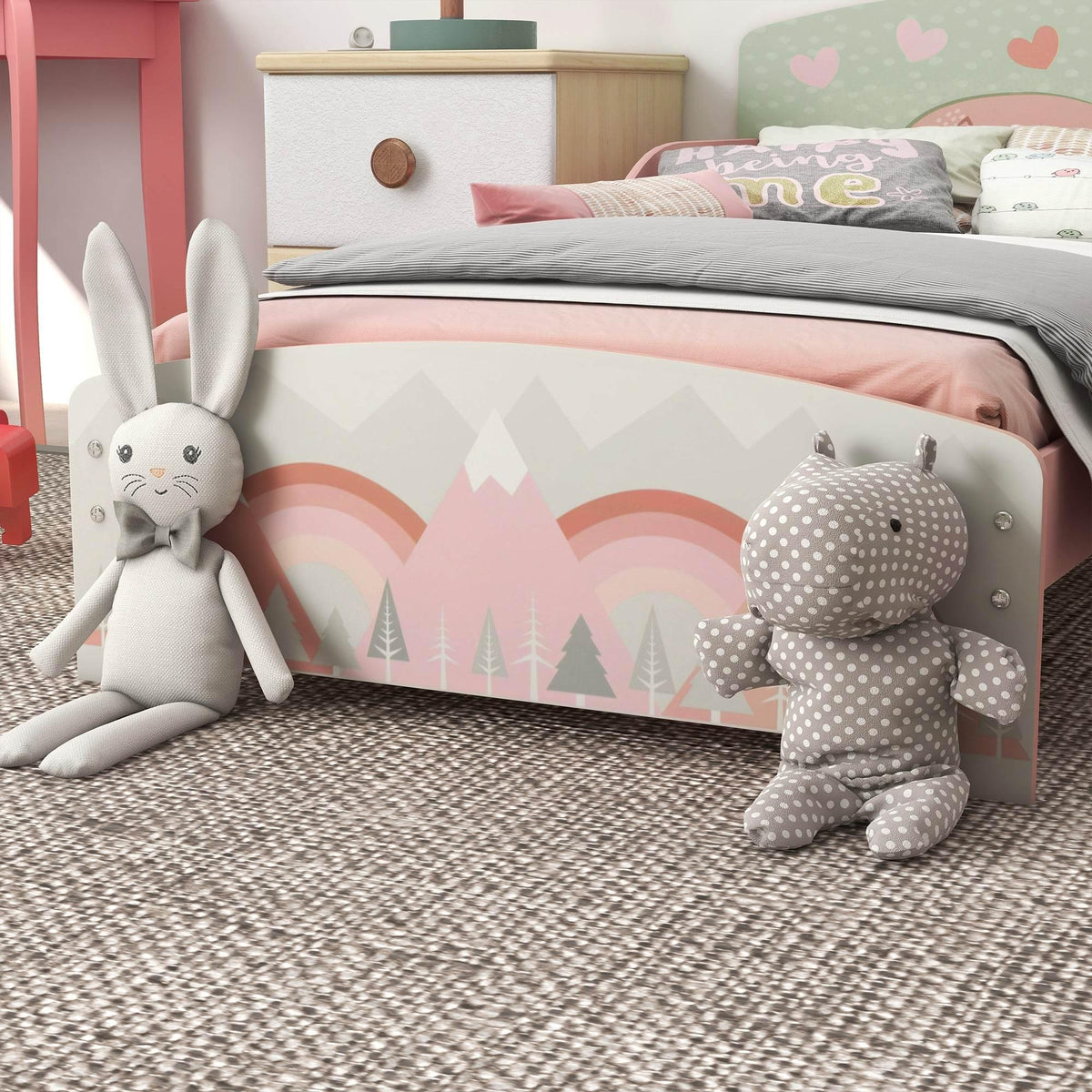 Pink kids bed with rainbow and tree print, plus stuffed bunny and bear.
